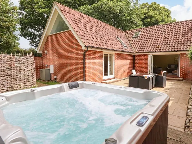 Oak Tree Lodge exterior with private hot tub on stone patio and open outdoor seating area