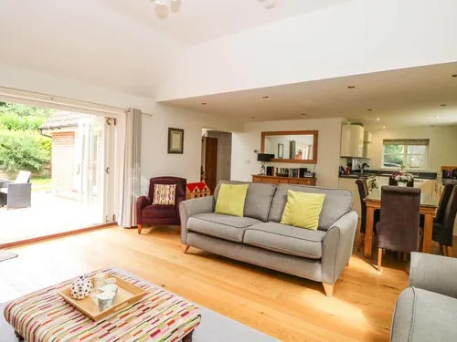 Lodge lounge with sofa, open-plan kitchen and dining area, doors to patio garden