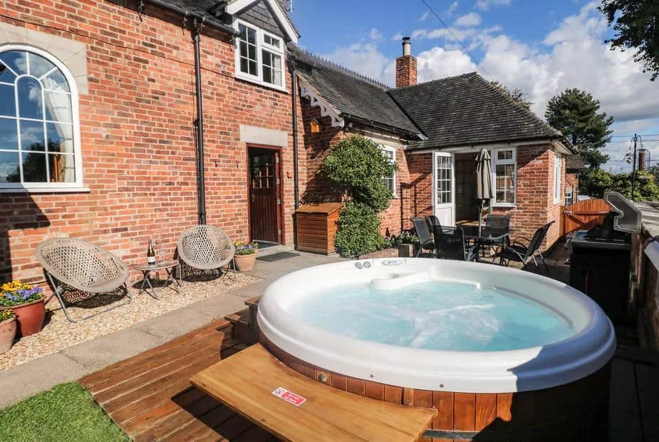 Orchard Cottage red-brick exterior with outdoor hot tub and patio seating
