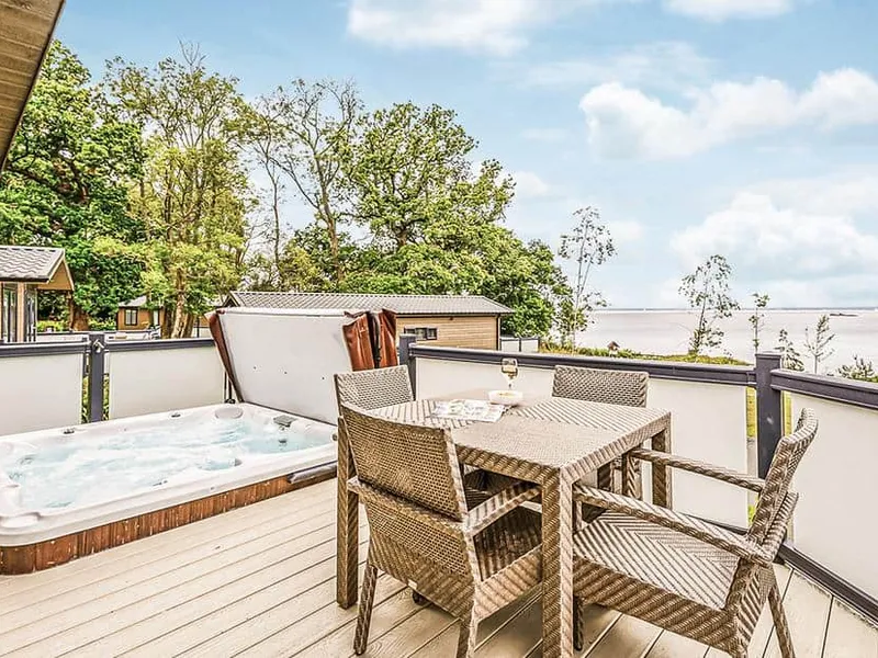 Deck at Osborne Premier Lodge with hot tub, outdoor dining set, and estuary views