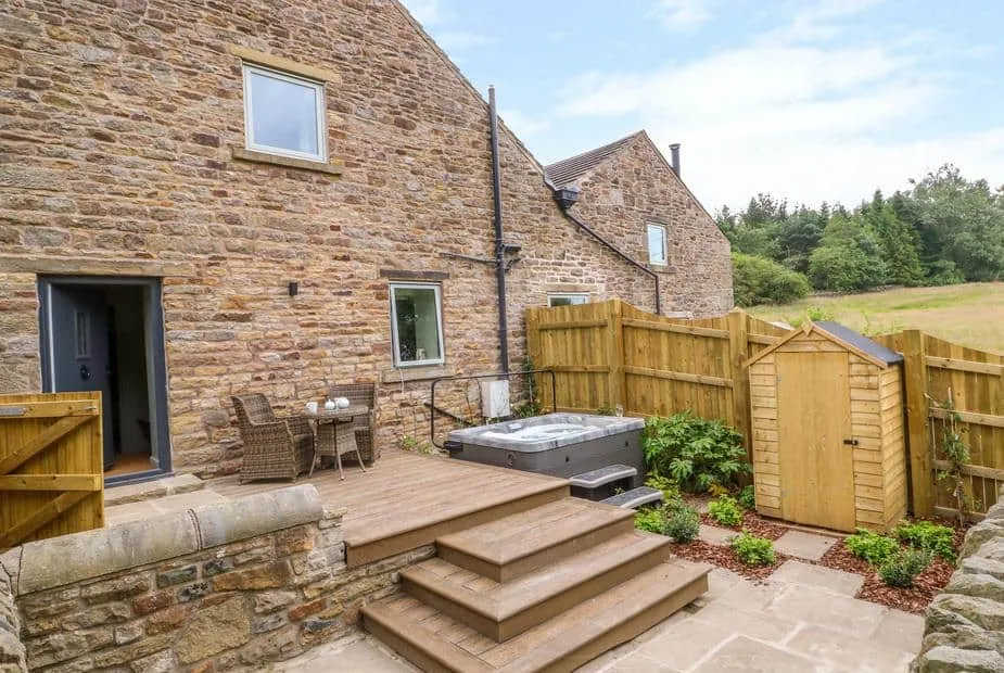 Overlea Barn stone exterior with hot tub and patio seating in enclosed garden