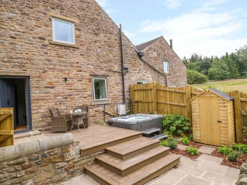 Overlea Barn stone exterior with hot tub and patio seating in enclosed garden
