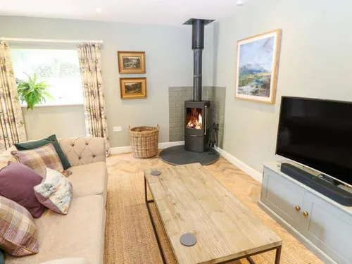Cottage lounge with wood burner, sofa, television and coffee table