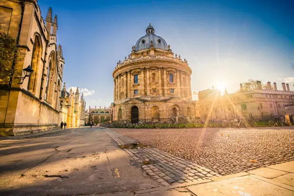Sunburst shining over the historic Radcliffe Camera and cobblestone streets in Oxford.