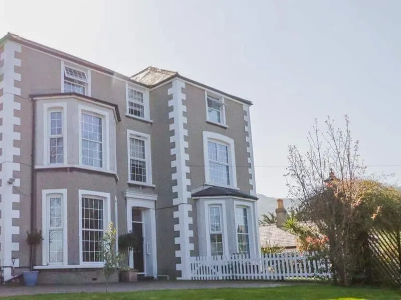 Penholm cottage exterior with large bay windows and white picket fence in front garden.