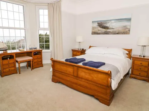Bedroom with sleigh bed and wooden desk by bay window