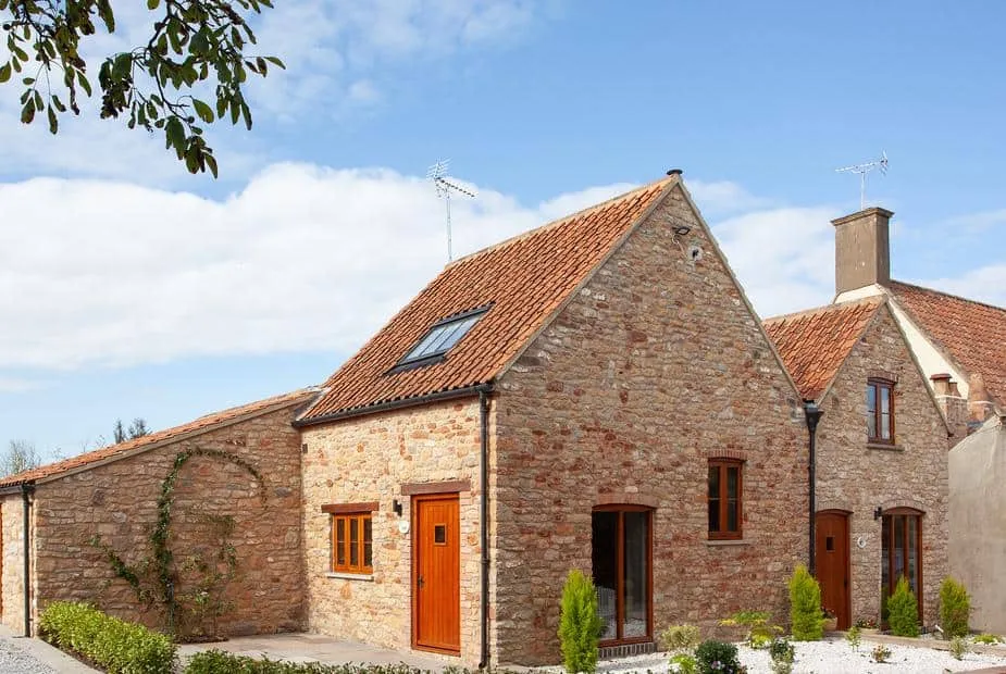 Poppy Cottage with stone exterior, red tiled roof, and small front garden