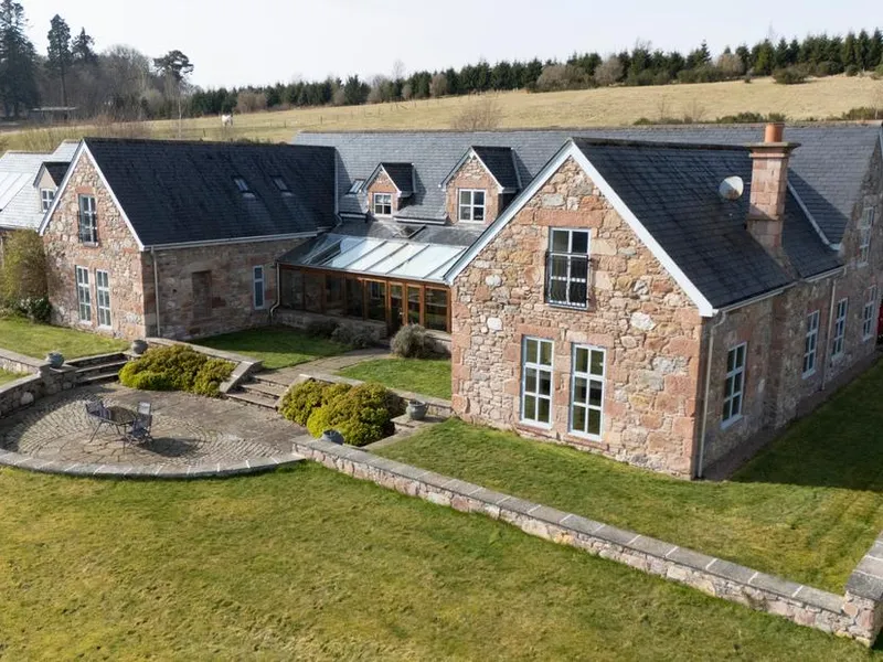 Aerial view of Quarryfield stone farmhouse with slate roof, glass atrium, and rolling Highland countryside
