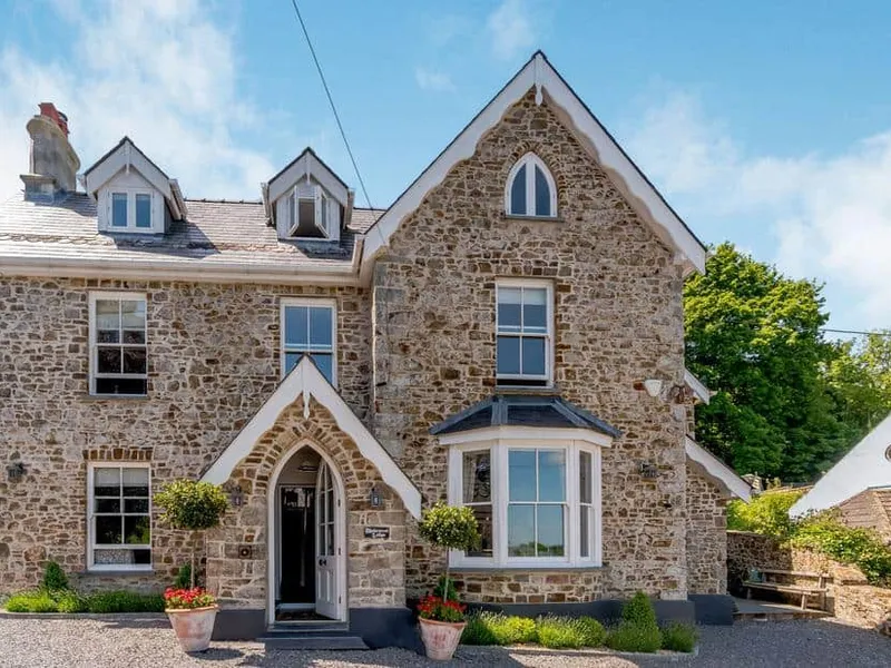 Rhodewood Lodge stone exterior with arched doorway and bay window facing the driveway