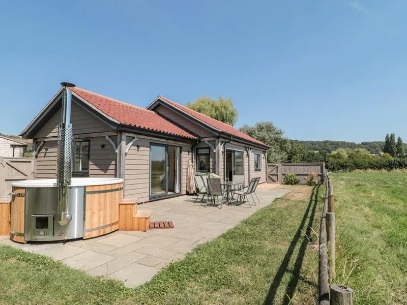 Robins Corner lodge with patio seating and outdoor hot tub overlooking open countryside.
