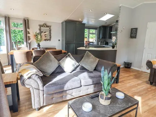 Lodge living area with grey sofa and coffee table facing open kitchen and dining table