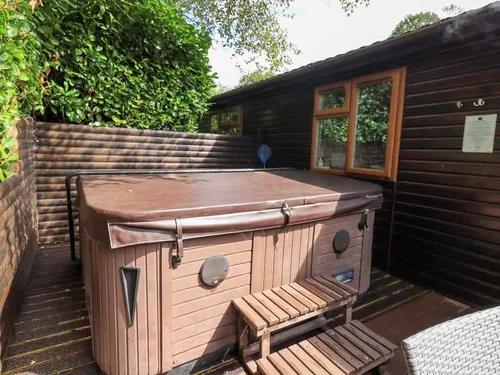 Lodge decking area with covered hot tub and steps