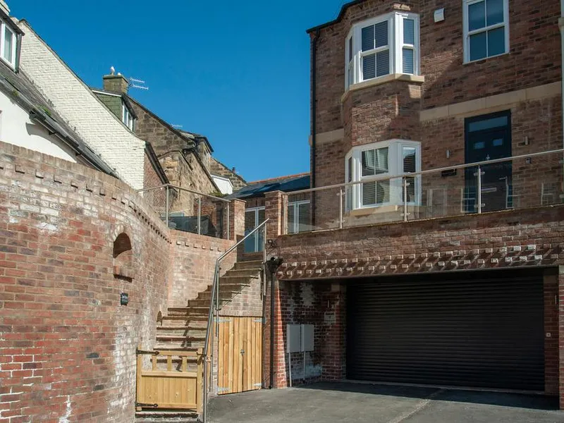 Salt Bay red brick end-terrace with garage, stone steps to entrance, and glass balustrade in Whitby