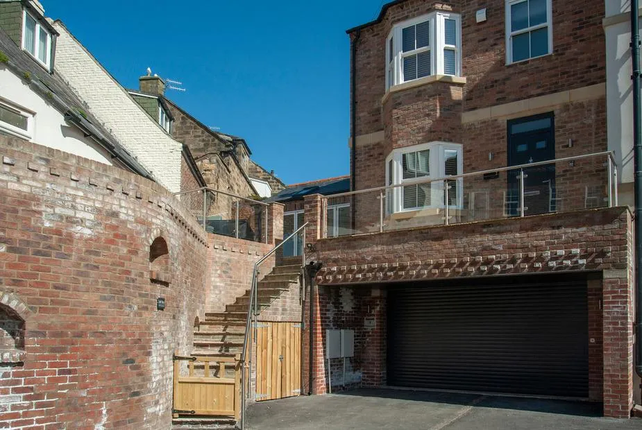 Salt Bay red brick end-terrace with garage, stone steps to entrance, and glass balustrade in Whitby