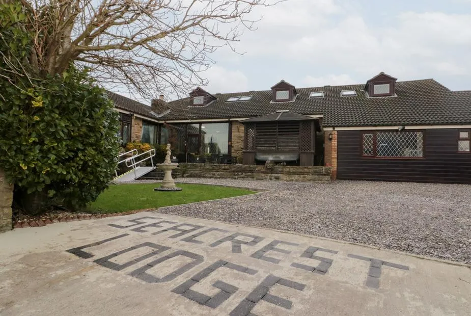 Seacrest Lodge dormer bungalow with stone and dark timber cladding, conservatory windows, and gravel driveway