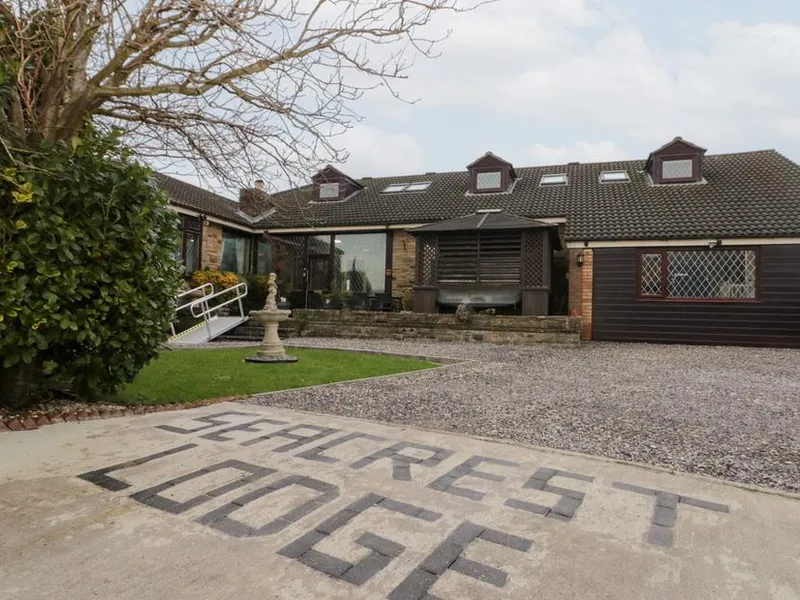 Seacrest Lodge dormer bungalow with stone and dark timber cladding, conservatory windows, and gravel driveway