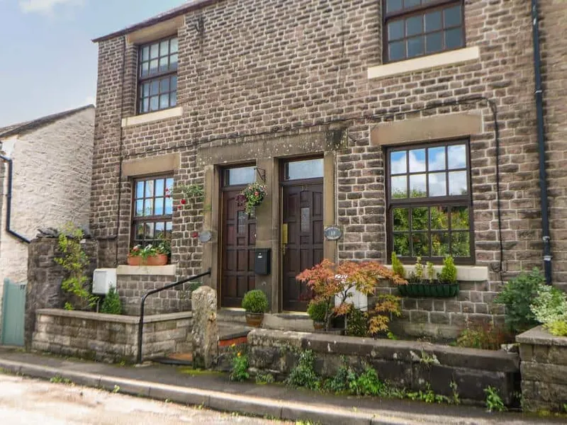 Shenton Cottage stone exterior with hanging baskets and potted plants by the entrance