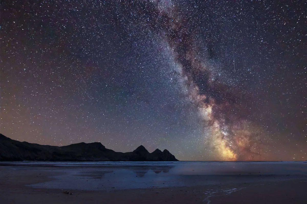 The Milky Way shining over the iconic Three Cliffs Bay on the Gower coast, South Wales.