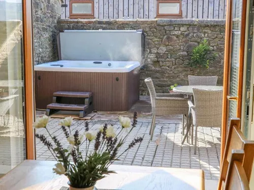 Cottage patio with hot tub and wicker table and chairs viewed from inside