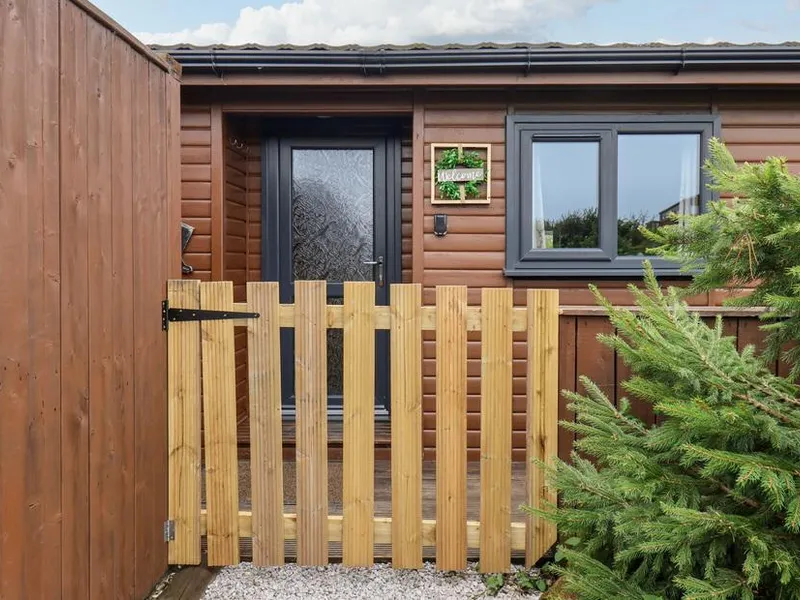 Stag Lodge Holiday Retreat timber cabin entrance with wooden picket gate and welcome sign