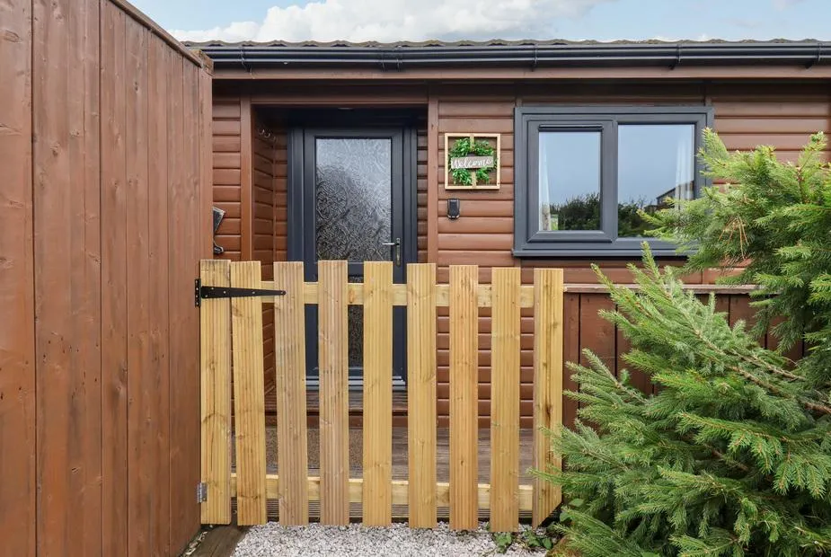 Stag Lodge Holiday Retreat timber cabin entrance with wooden picket gate and welcome sign