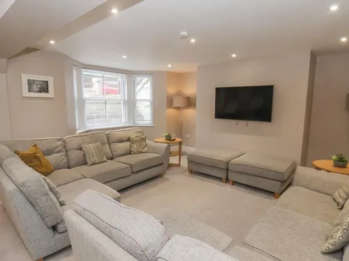 Sitting room with grey fabric sofas arranged around a wall-mounted TV and bay window