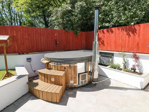 Cottage patio with wooden hot tub and red fence