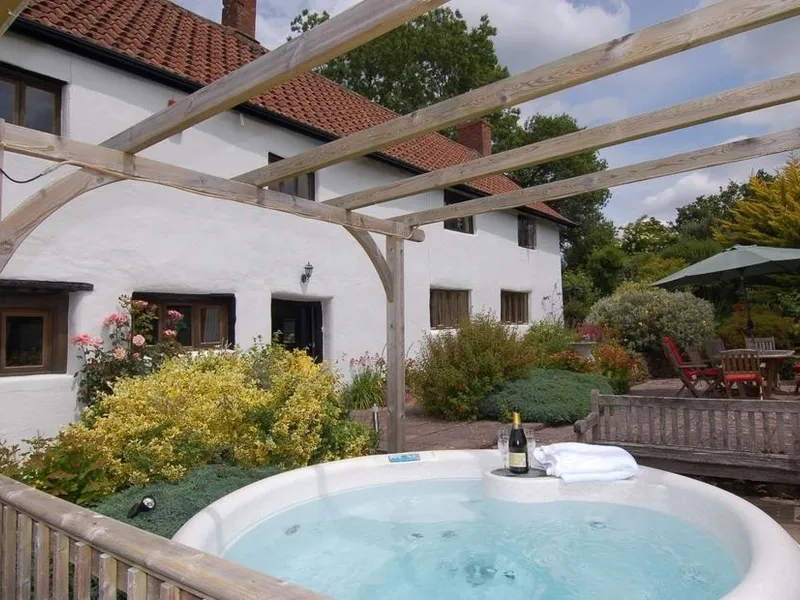 A hot tub on a patio in front of the farmhouse