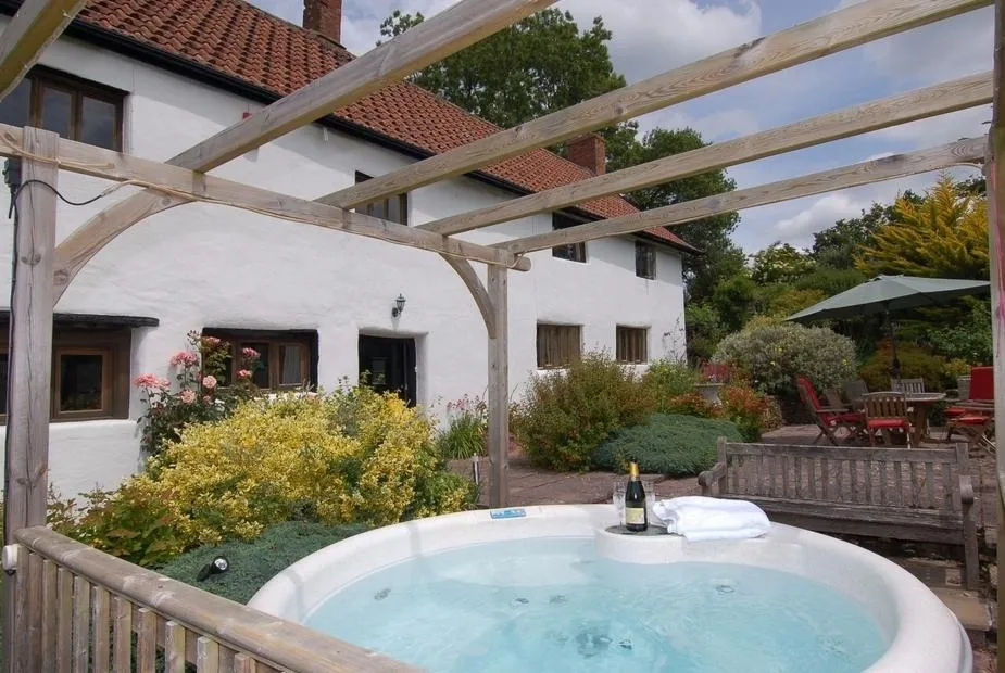 A hot tub on a patio in front of the farmhouse
