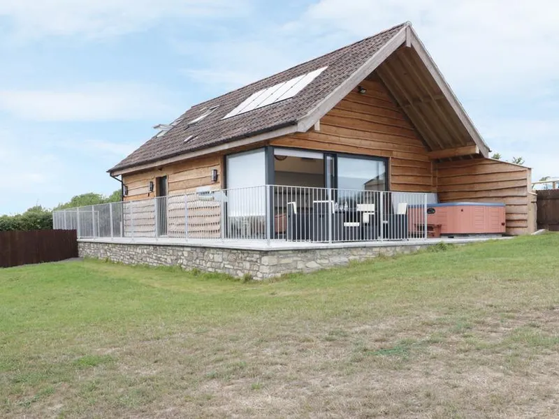 Swan Lodge timber-clad lodge with stone base, raised deck, and hot tub on Castle Farm near Wedmore