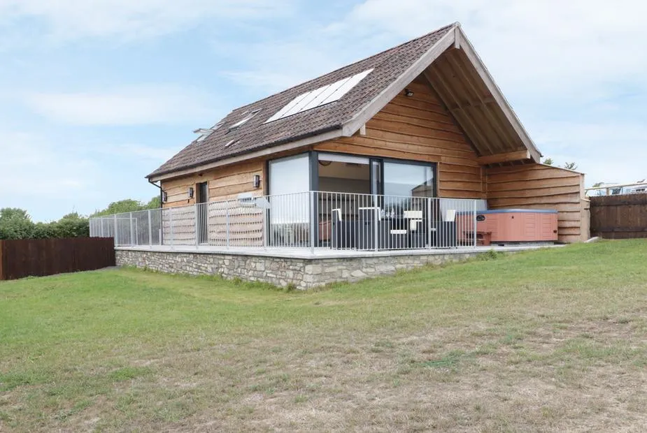 Swan Lodge timber-clad lodge with stone base, raised deck, and hot tub on Castle Farm near Wedmore