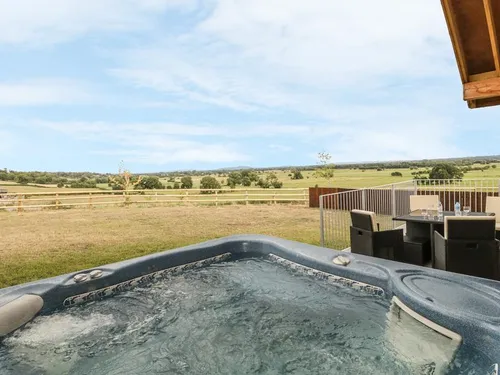 Hot tub on the sheltered patio with outdoor dining furniture and views across the Somerset Levels