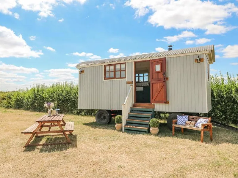 Sweet Caroline Shepherd’s Hut with outdoor bench and picnic table on grassy field