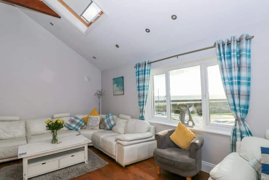 Swn y mor lounge with white sofas, skylight, and large window showing sea views