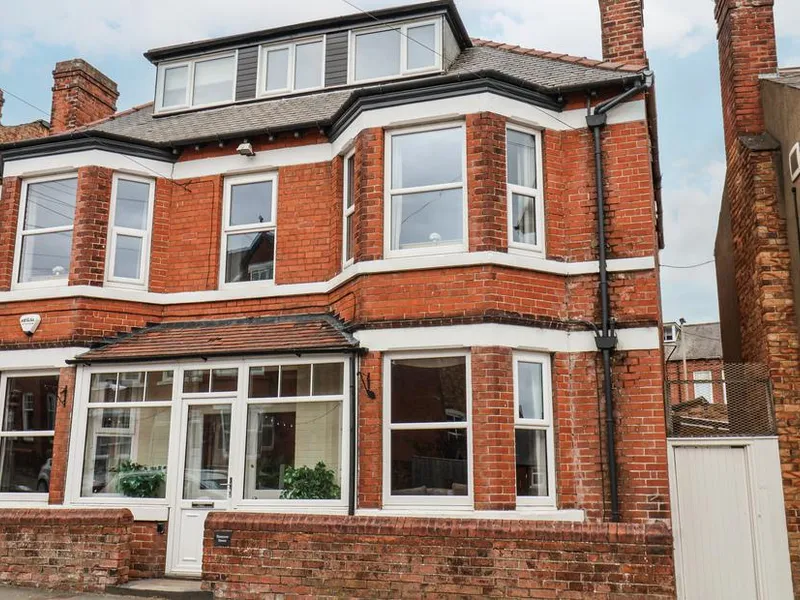 Tennyson House, a three-storey red brick town house with bay windows and white frames on a Scarborough street