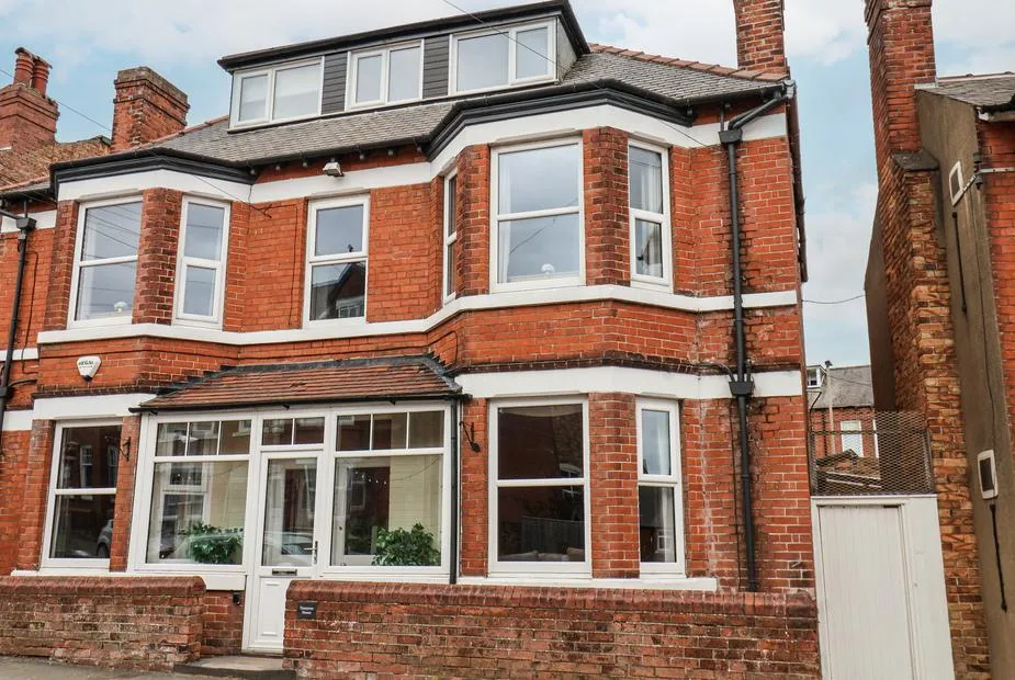 Tennyson House, a three-storey red brick town house with bay windows and white frames on a Scarborough street