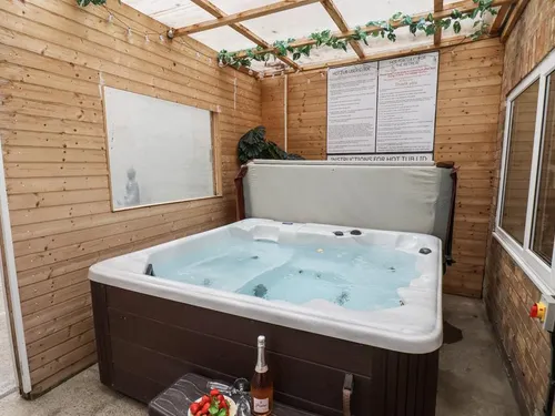 Bubbling hot tub in a timber-clad shelter with a window looking back towards the house