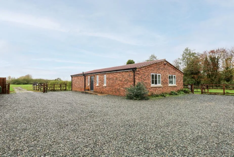 The Apple Shed brick cottage with gravel driveway and countryside views