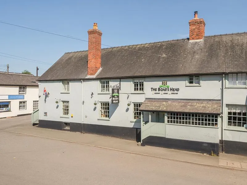 The Boars Head Pub exterior with sign and two red brick chimneys
