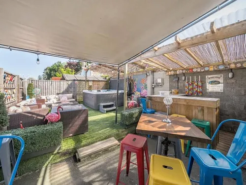 Covered patio area with bar, hot tub and seating in cottage garden