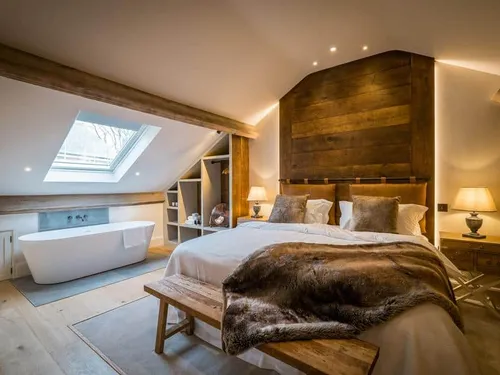 Cottage bedroom with double bed and freestanding bath under skylight