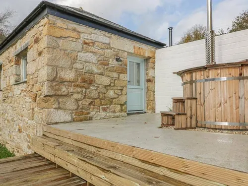 Cottage stone exterior with wooden hot tub on raised decking
