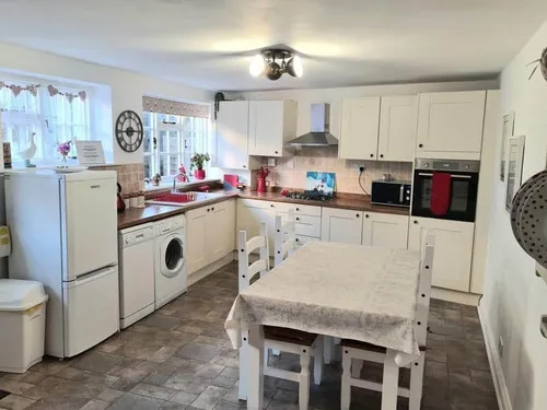 Cottage kitchen with dining table, washing machine, and fitted oven.