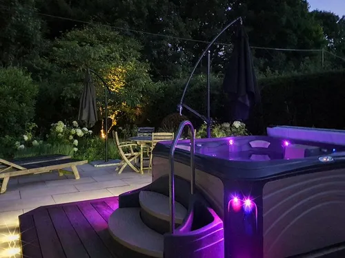 Cottage patio with hot tub and seating area at dusk