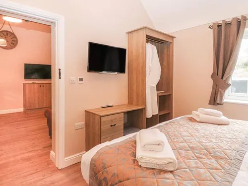 Cottage bedroom with double bed, TV, wardrobe and window with curtains