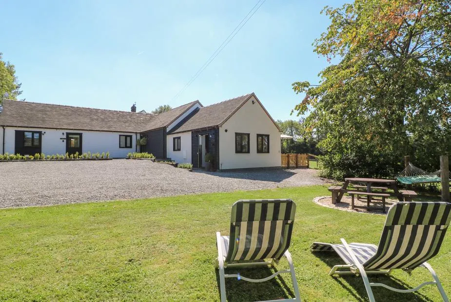The Den exterior with lawn chairs, picnic table and hammock in the garden