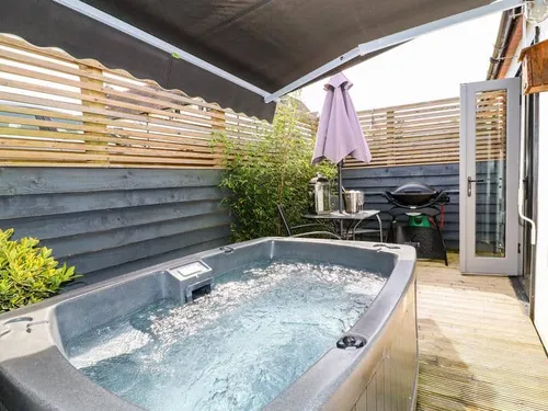 Cottage patio with hot tub, outdoor table and barbecue grill