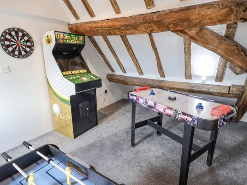 Cottage games room with arcade machine, air hockey table and dartboard