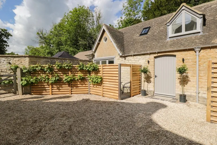The Hayloft with gravel courtyard and timber privacy screens with climbing plants