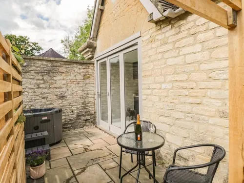 Cottage patio with bistro table, chairs and hot tub by stone wall